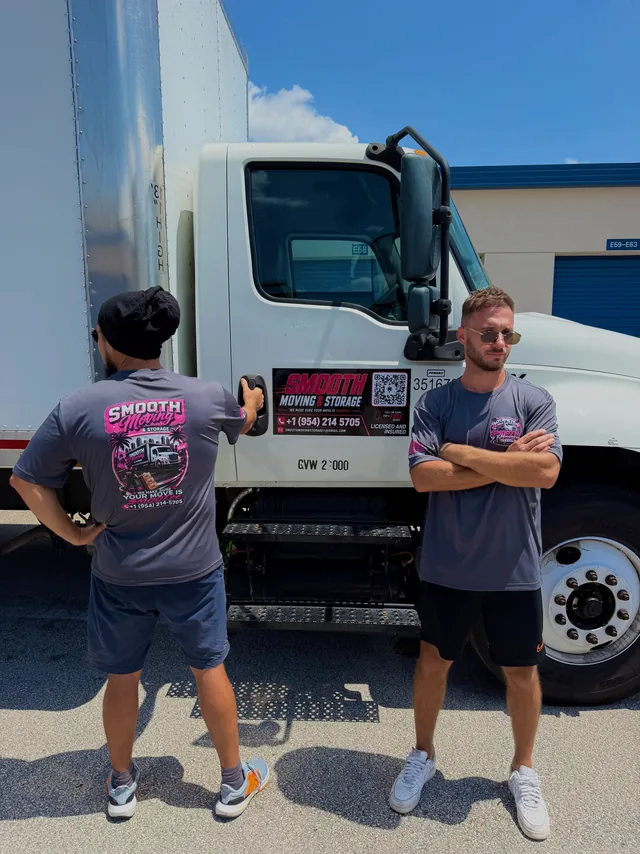 Two Smooth Moving crew members in branded shirts beside the company truck