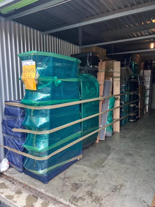 Furniture wrapped in moving blankets and shrink, strapped in stacks
